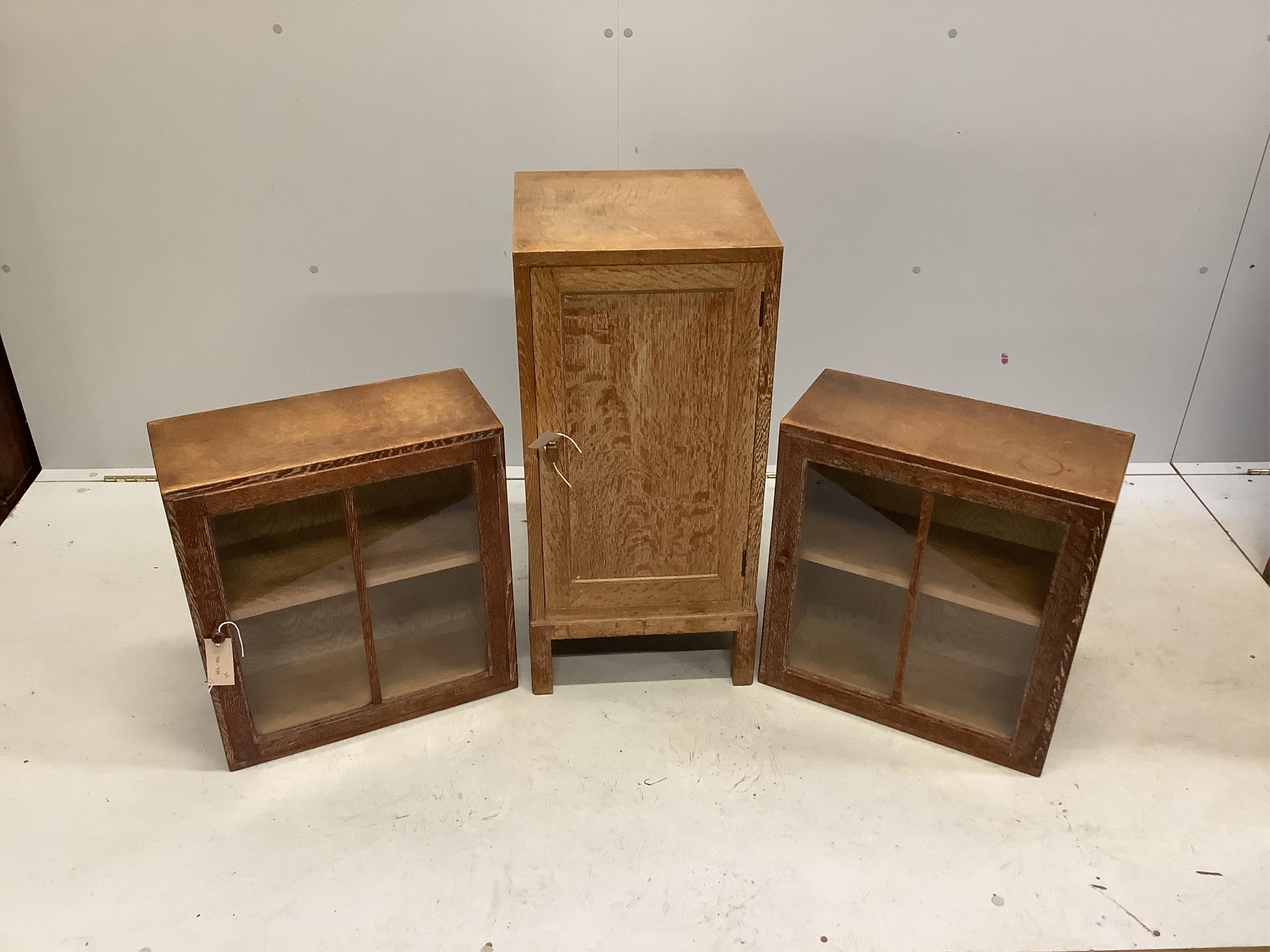 Heal & Son Ltd. A pair of weathered oak wall cabinets, width 45cm, depth 21cm, height 50cm together with a Heals oak bedside cupboard, width 36cm, height 76cm. Condition - fair to good